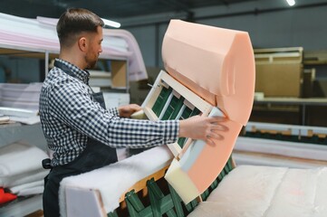 Furniture maker assembling sofa in upholstery workshop
