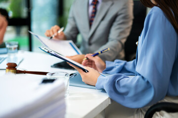 Business and lawyers discussing contract papers with brass scale on desk in office.