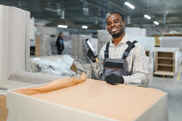 African american Furniture maker upholstering sofa in factory
