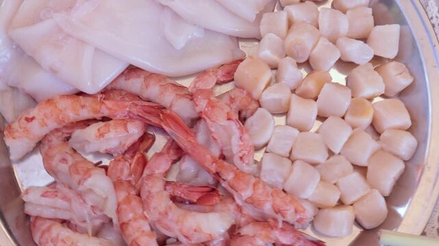 Scallops without shells, shrimp and squid on a plate, cooking seafood