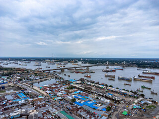 Aerial view of river with bridge, boats and buildings. Hundreds of vessels are seen anchored in Karnafuli River near Port in Chattogram, on the coastline of the Bay of Bengal.