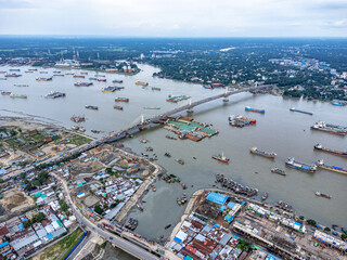 Aerial view of river with bridge, boats and buildings. Hundreds of vessels are seen anchored in Karnafuli River near Port in Chattogram, on the coastline of the Bay of Bengal. © Zakir Hossain