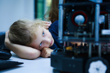 Young student with blue eyes watching robot mechanism attentively, representing calm engagement and...