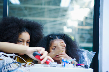African American girls concentrating on electronic components in a STEM classroom, actively engaged...