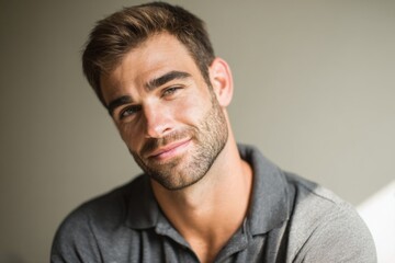 Obraz premium Confident Smiling Young Man with Beard and Casual Collared Shirt in Indoor Setting.