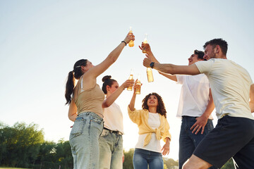 People are celebrating by cheering with beer bottles