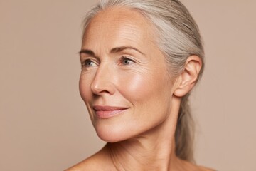 Close-up portrait of a mature woman with silver hair smiling gently, wellness and beauty concept.