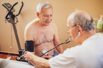 Patient is having exam at cardiologist. Doctor is measuring blood pressure to his patient.