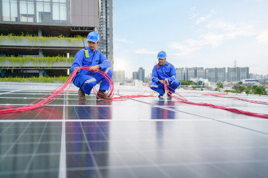 Electrical engineer inspecting and installing a solar panels on the building rooftop.