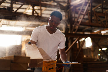 Professional African male carpenter is working professionally in sawmill - workshop.