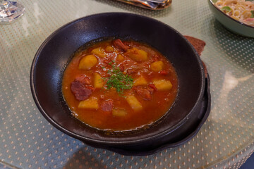Thick soup-stew bograch in black metal thick-walled bowl
