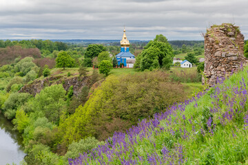 Steep riverbank with old ruins on foreground and wooden church