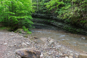 Steep bank of mountain river with layered structure of rocks