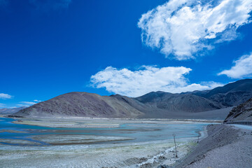 A vivid landscape featuring a meandering river cutting through a barren high-altitude desert, set...