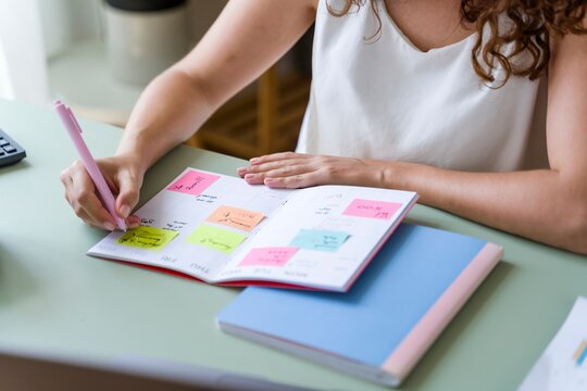 Woman with curly hair writing in planner at home office desk