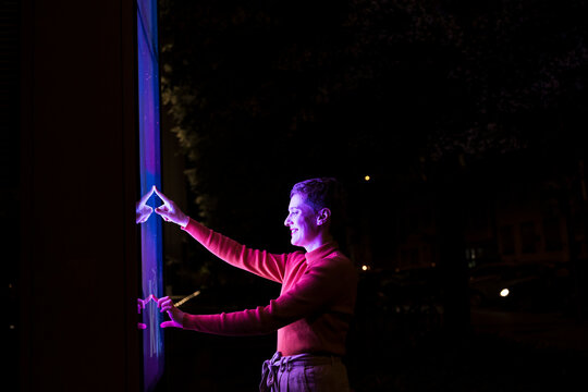 Expressive person interacting with city information screen at night