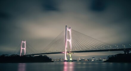 Obraz premium A majestic suspension bridge is illuminated with pink lights at night spanning