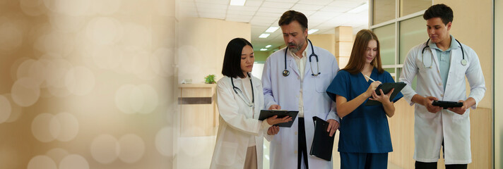 A group of doctors, nurses and staff pose for a photo in a hospital corridor.