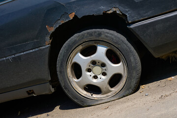 Old messy car with a rusty wing,a flat tire