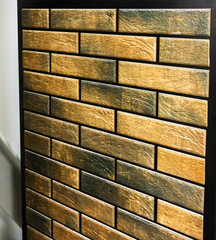 Close-up of a textured wall covering made of rectangular tiles mimicking rustic bricks. Features a...