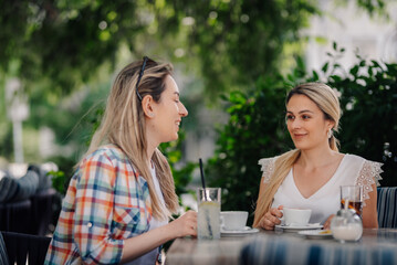 Two women talking and drinking coffee at outdoor cafe