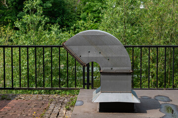 Metallic ventilation structure surrounded by greenery on a sunny day