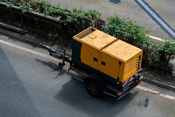 Yellow utility trailer parked beside a busy roadway
