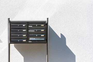 Modern metal mailbox structure against a clean wall