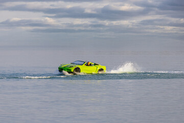 A young man glides across the water on a jet ski designed like a car, enjoying summer waves....