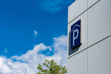 Parking sign on white parking garage under a cloudy blue sky