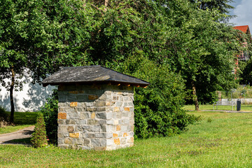 Stone small structure in a green park on a sunny day