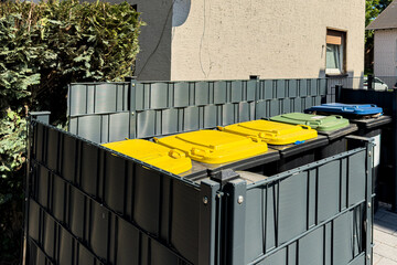Recycling bins organized behind a residential building.