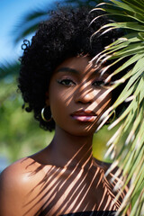 Fashion beauty portrait. Shadows of palm leaves play across the face of an African American woman...