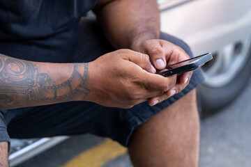 Close-up of a worker using smartphone during a break, showcasing a detailed tattoo on his arm