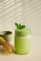 matcha mint jam jar cocktail with bamboo whisk and ceramic bowl in sunlit kitchen with space for text concept of modern drink ritual cafe design content