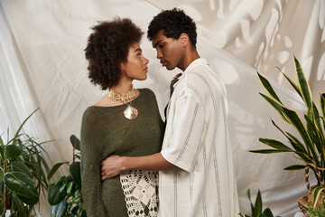 Young couple sharing a tender moment amidst stylish indoor greenery and artistic decor