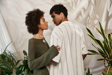 Young couple sharing a tender moment amidst lush greenery in a cozy setting