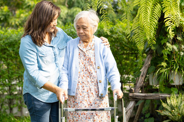 Caregiver help and care Asian senior woman  walk with walker at park.