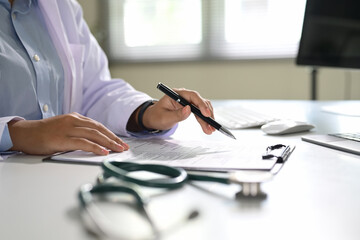 Doctor filling out patient information on a clipboard at a modern desk