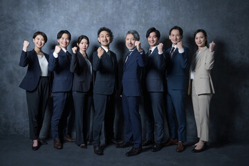Eight full-body businessmen standing side by side, looking at the camera, gut-posed.