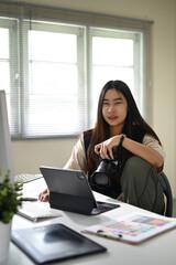 Portrait of female photographer sitting confidently at her creative workstation