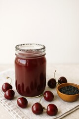 dark cherry cocktail with black salt rim and crushed ice in mason jar on wooden table, surrounded by fresh cherries,  wooden bowl of smoked salt, rustic summer drink concept