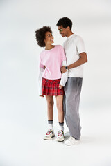 Young couple sharing a joyful moment in stylish outfits against a clean backdrop