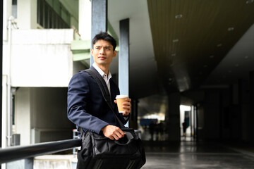 Confident businessman standing with coffee and looking ahead with determination