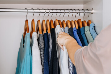 Woman sorting shirts in stylish minimalist wardrobe