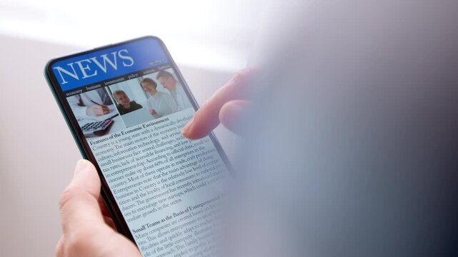 Reading news on the phone screen holding it in your hand. Online press on your smartphone. Concept of media information in digital technology.