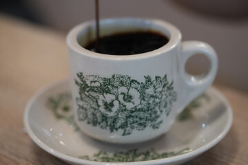 Swirling Cream in Ceramic Coffee Cup with Green Patterns