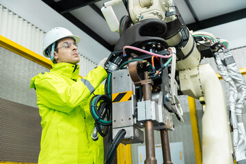 Repairman checking hardware robotic arm system of automation machine in factory. Service...