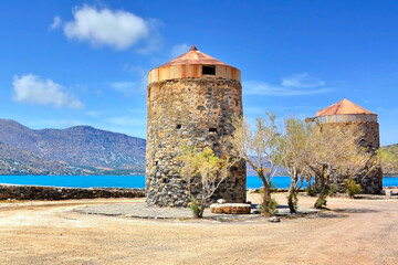 Remains of two old, stones windmills near town of Elounda, Crete, Greece