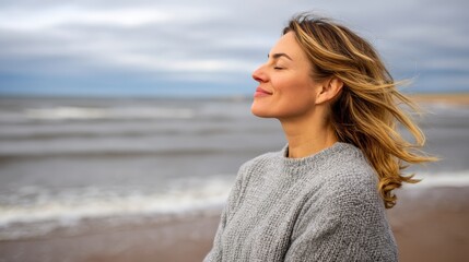 Medium side view of a peaceful woman standing at a breezy coastline with windswept hair, closed eyes, and gentle waves crashing under cloudy skies, creating a serene and tranquil atmosphere